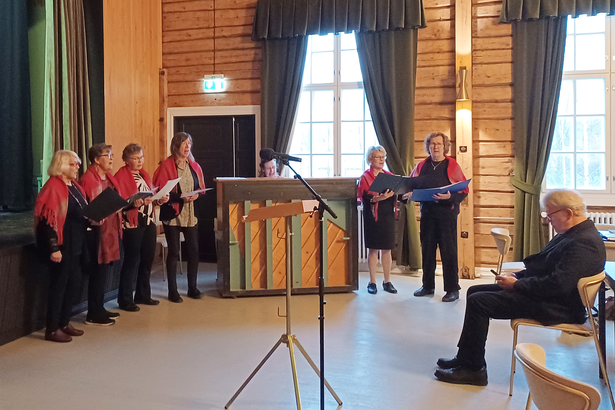 Ellien kuoro ensiesiintymisessään. Kuvassa Elvi Kukkonen, Reetta Toivanen, Kirsti Puhakka, Kristiina Tallgren, Ritva Paananen (piano), Anne Hamunen ja Arja Tanskanen. Etualalla kirkkoherra Huhtala.
