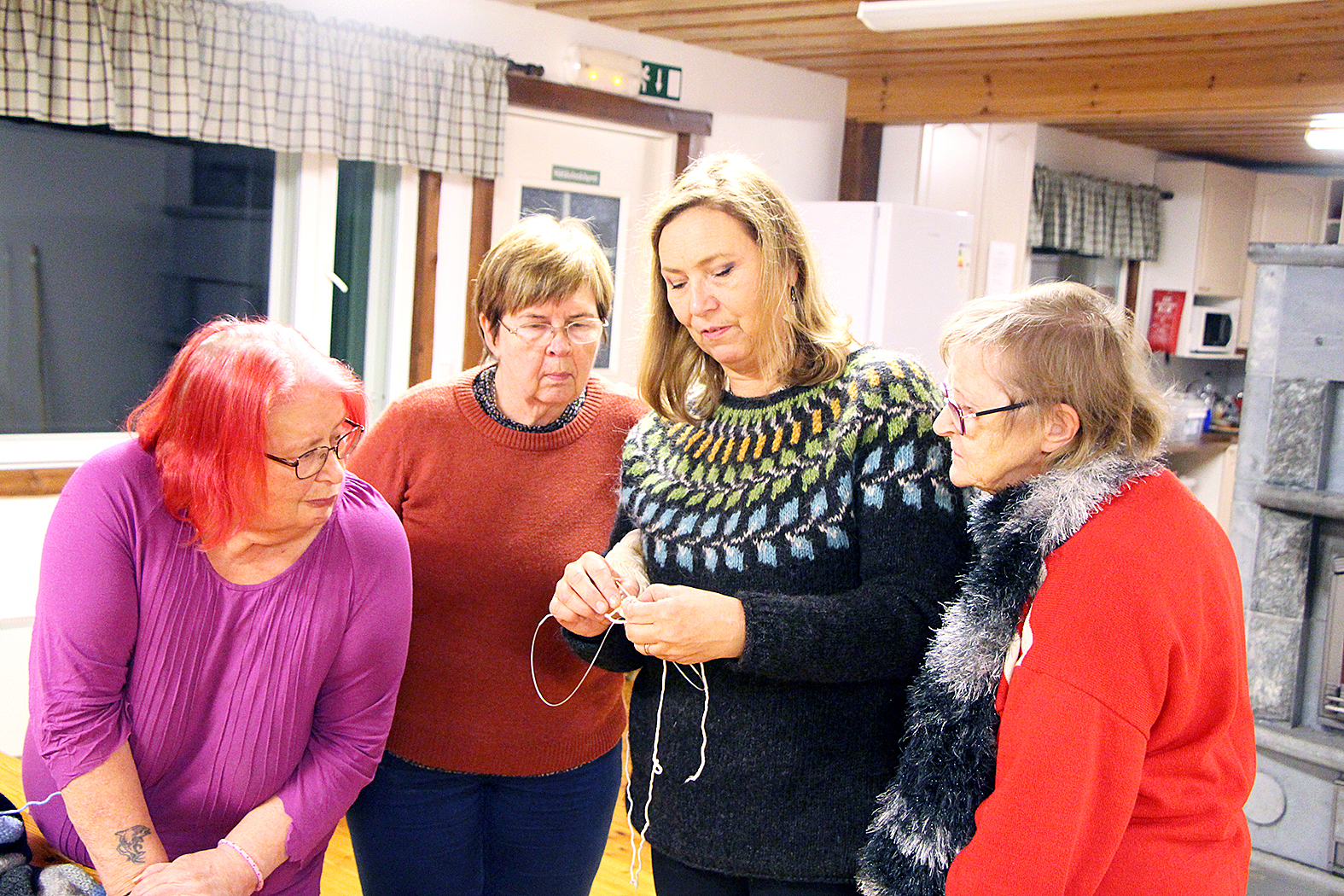 Päivi Pennala näyttää Arja Oksmanille (vas.) Irene Tuonoselle ja Liisa Pehkoselle, kuinka kinnasneulaa käytetään. 
