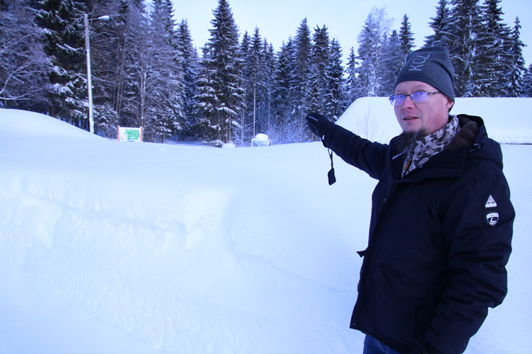 Sami Pakarinen osoittaa Ahmovaaran koulun pihassa metsänrajaa, josta Ahmanhiihtoon osallistuvat, tai osa heistä, hiihtää huolto- ja lähtöpaikalle.
