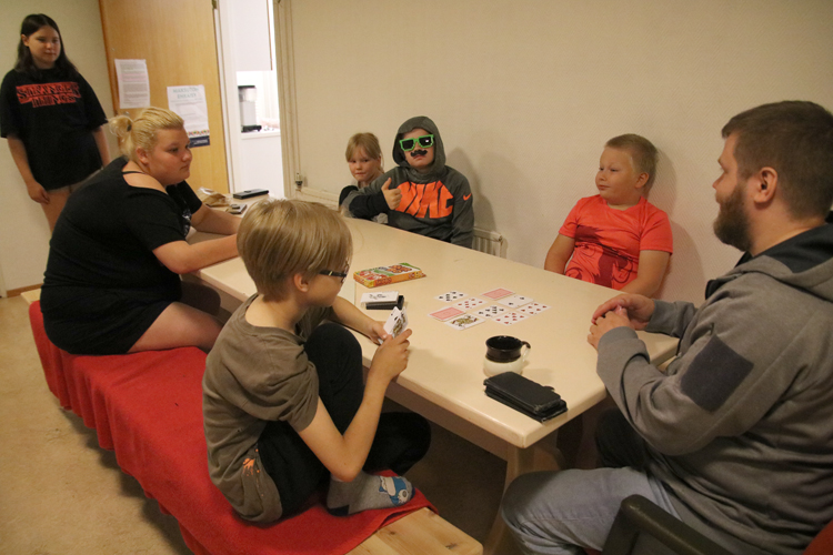 Ristiseiskaa nuokkarilla. Etsivä nuorisotyöntekijä Vesa Savolaisen johdolla kesäleirillä pelattiin asiaankuuluvasti myös korttia. Pöydän äärellä Lauri Tulkki (takana), Topi Toivanen ja Siiri Rajala. Edessä Peeti Kortelainen, nuorisotyöntekijä Tiina Timonen sekä Moona Kettunen.
