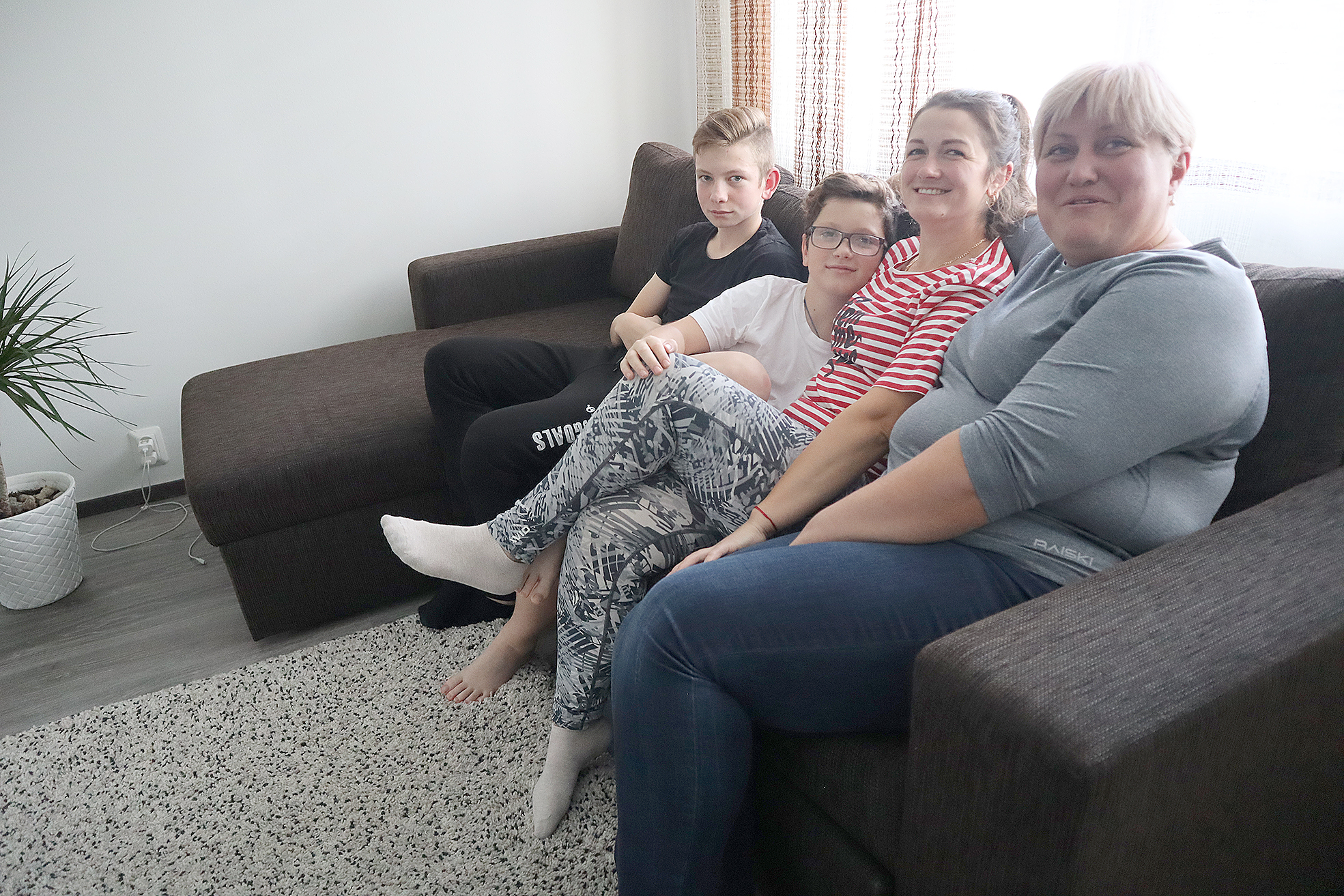 Pakolaisperhe kotisohvalla. Pojat Aleksanteri ja Denis Potrebish istuvat kotisohvalla äitinsä Tamara Karpenkon ja Marina Matviitchoukin kanssa.