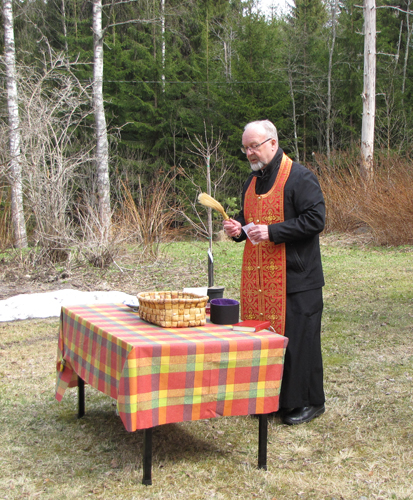 Isä Sulo Naakka Nurmeksen ortodoksisesta kappeliseurakunnasta siunasi vakallisen siemeniä pyhitetyllä vedellä.
