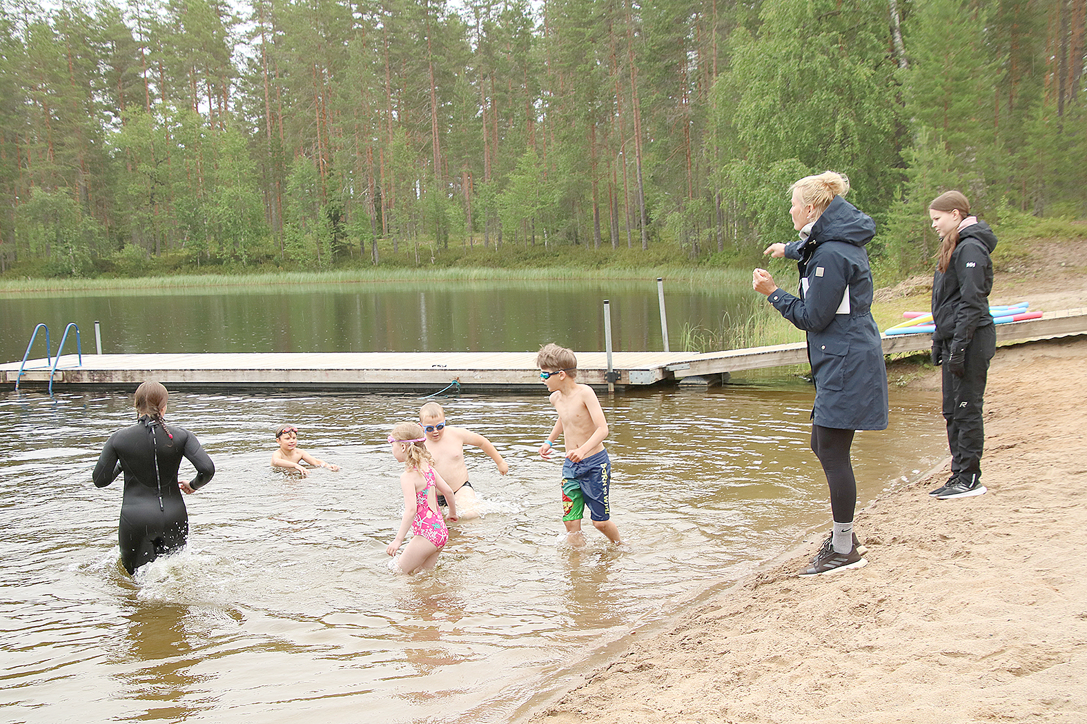 Liikunnanohjaaja Mari Ovaskainen avusti lapsia vedessä, kun vapaa-aikakoordinaattori Riitta Karppinen ohjasi opetusta rannalta käsin Moona Salmen seuratessa vierellä. 